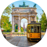 Un tram giallo storico attraversa il centro di Milano con l'Arco della Pace e il Castello Sforzesco sullo sfondo.