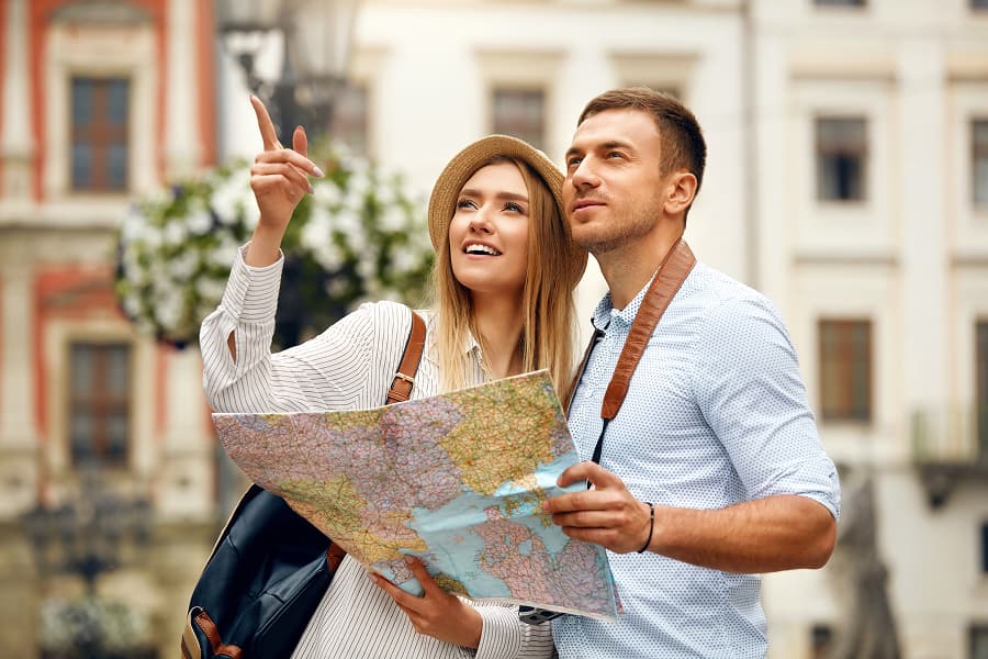 Due viaggiatori con zaino e mappa esplorano una città, orientandosi tra strade storiche e architettura colorata.