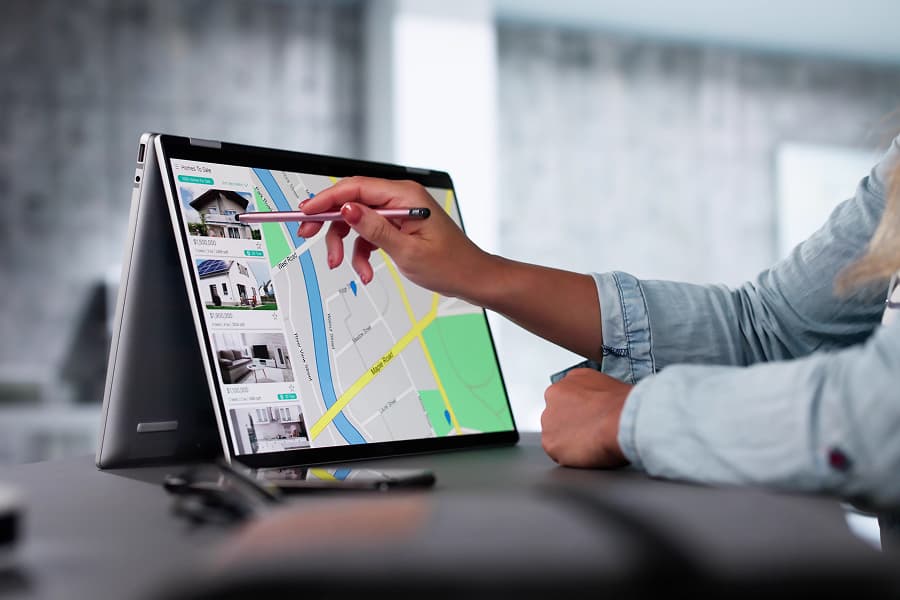 Person using a tablet to consult a digital map of a city, highlighting various routes and points of interest, in a bright, modern environment.