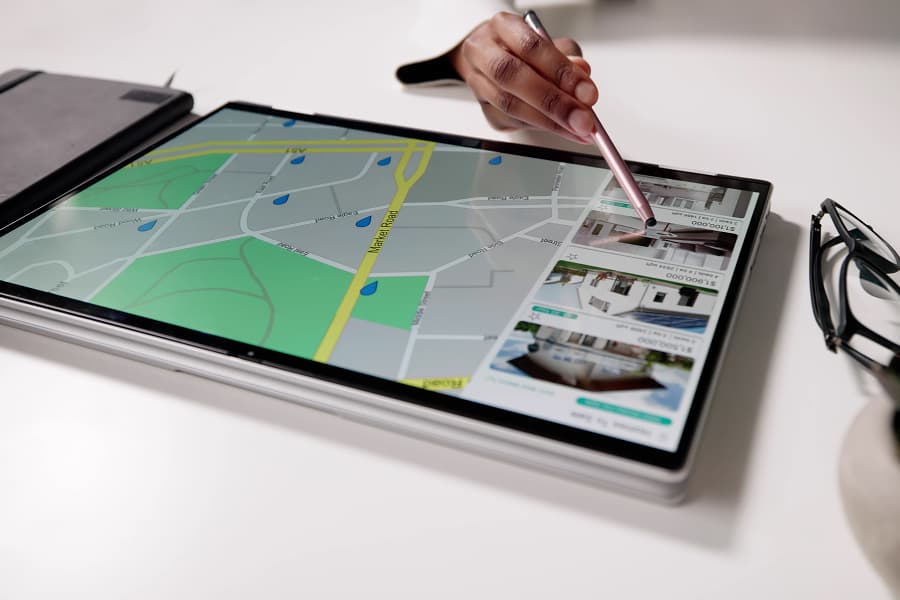Person using a touchscreen tablet with a pen to navigate a digital map and view property listings or details