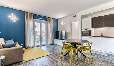 Foto di un ampio living con cucina a vista, tavolino rotondo con sedie gialle e divano con cuscini blu